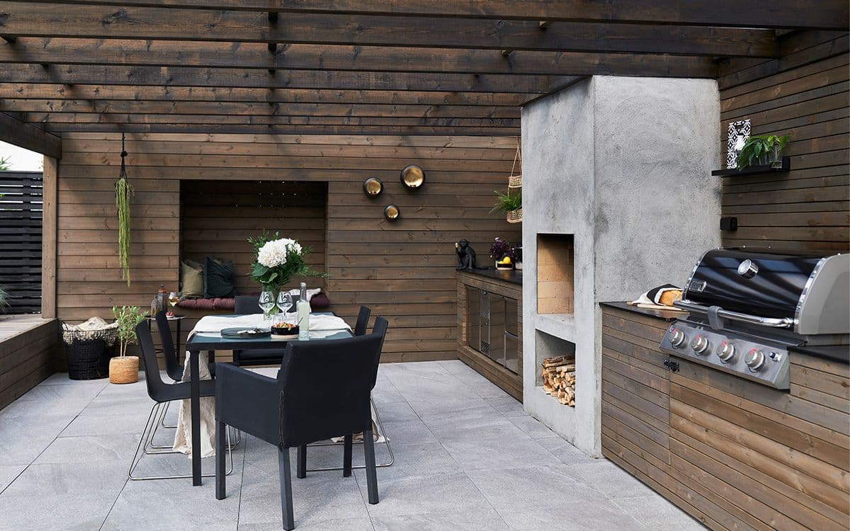 Terrasse med peis, pergola, utekjøkken og levegg i Concise-serien til MøreRoyal.