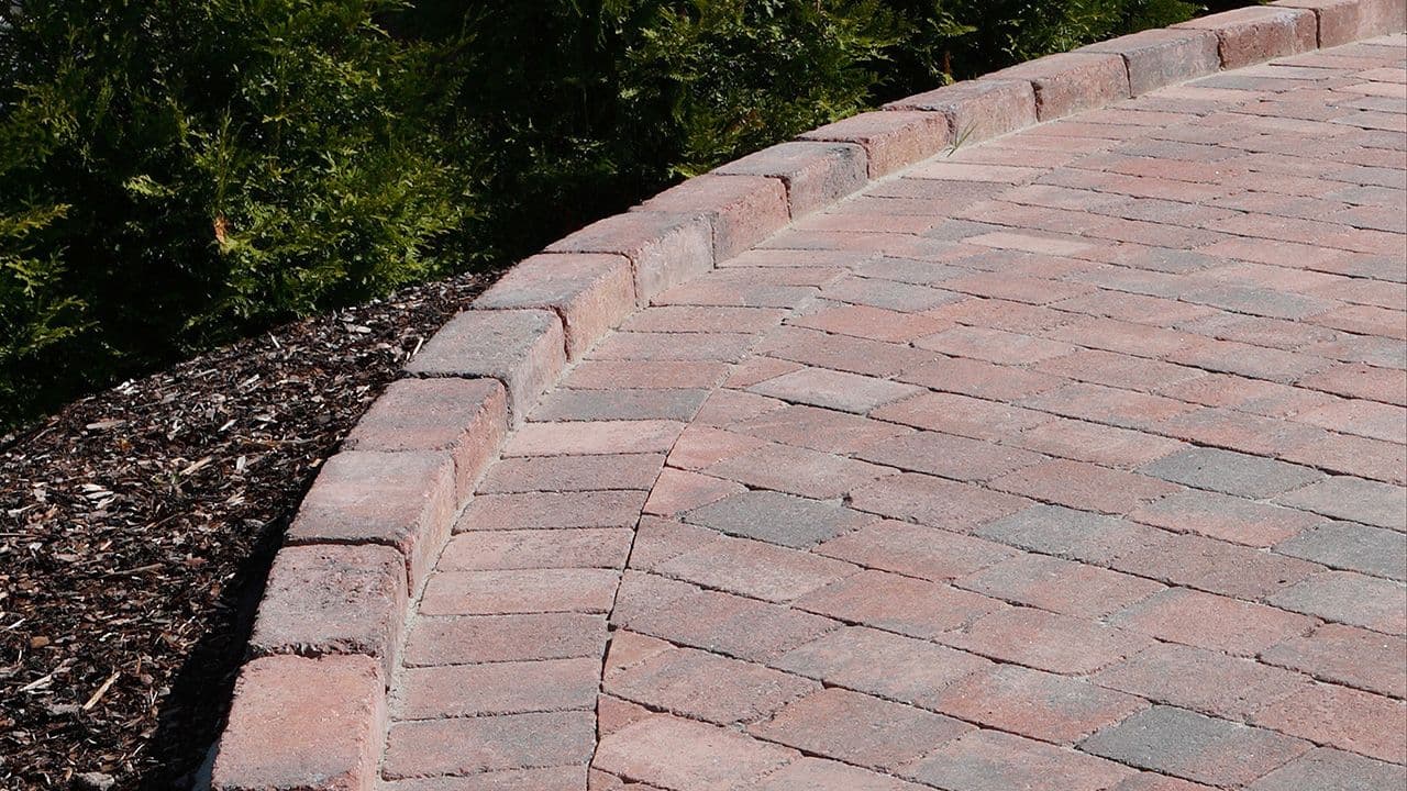 Gårdsplass med belegningsstein i rødmix lagt i bue.