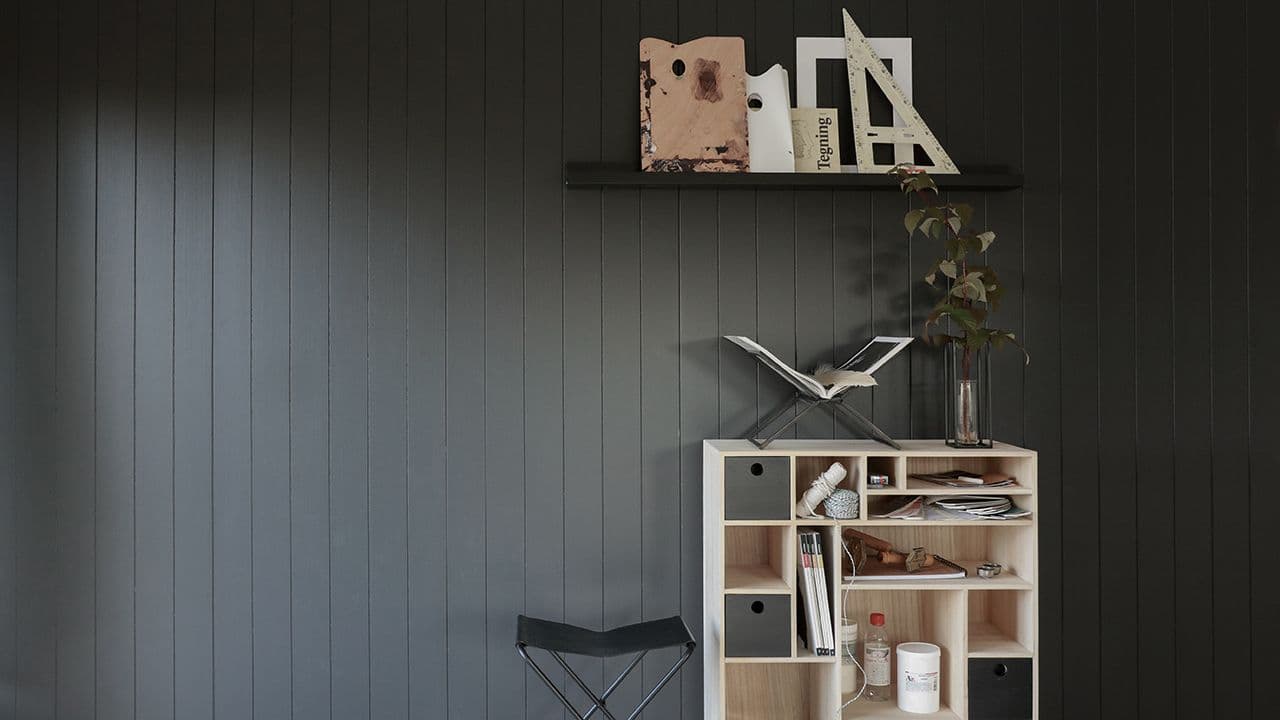 Stuevegg med Huntonit veggplater i Dempet Sort kombinert med sorte og lyse tremøbler.