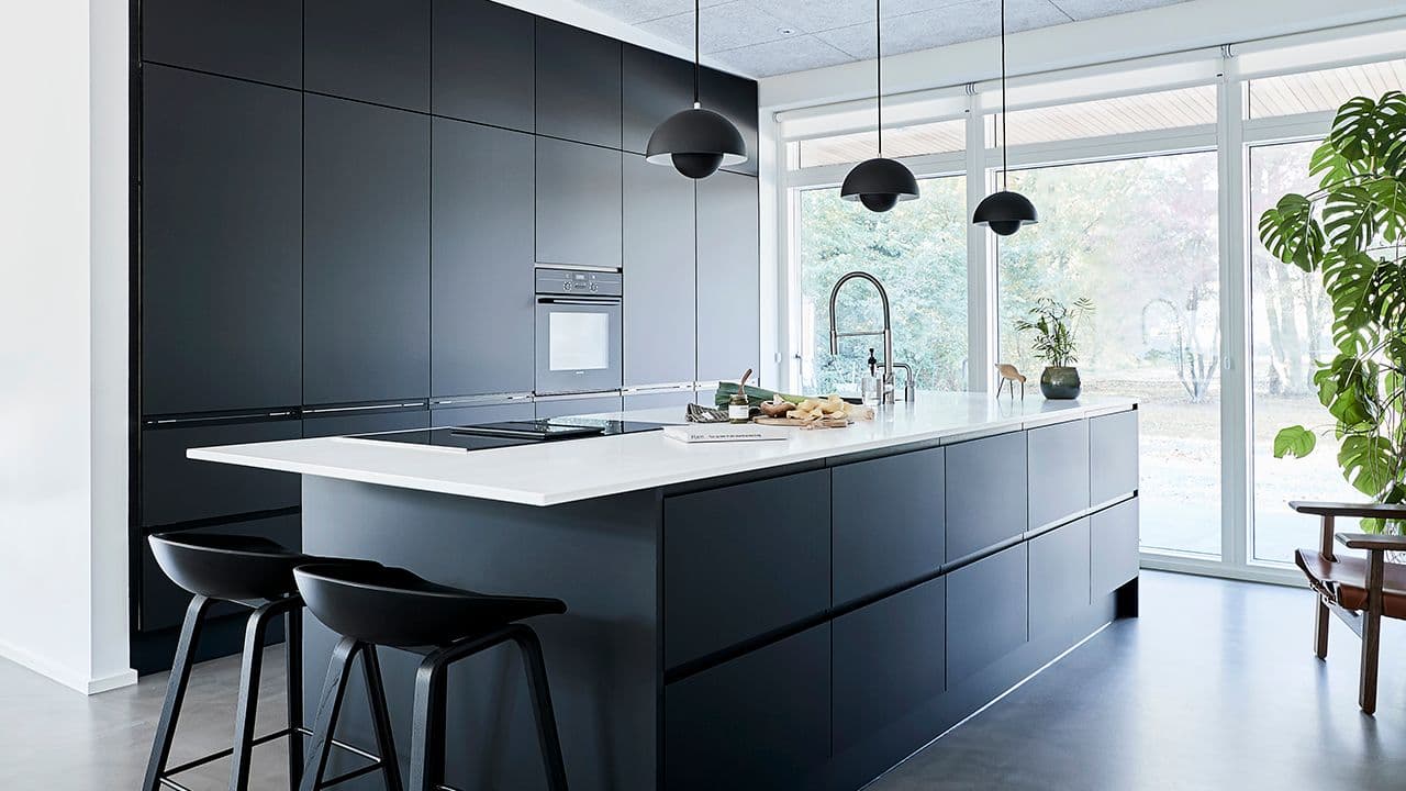 Kjøkken med kjøkkenøy med mørk innredning.