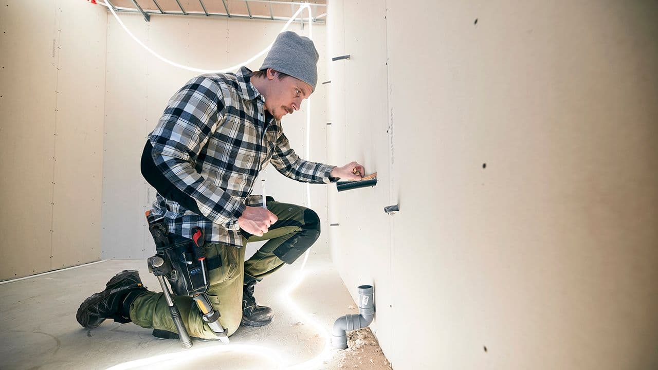 Håndverker som jobber innendørs med LED-lyslist som arbeidslampe.