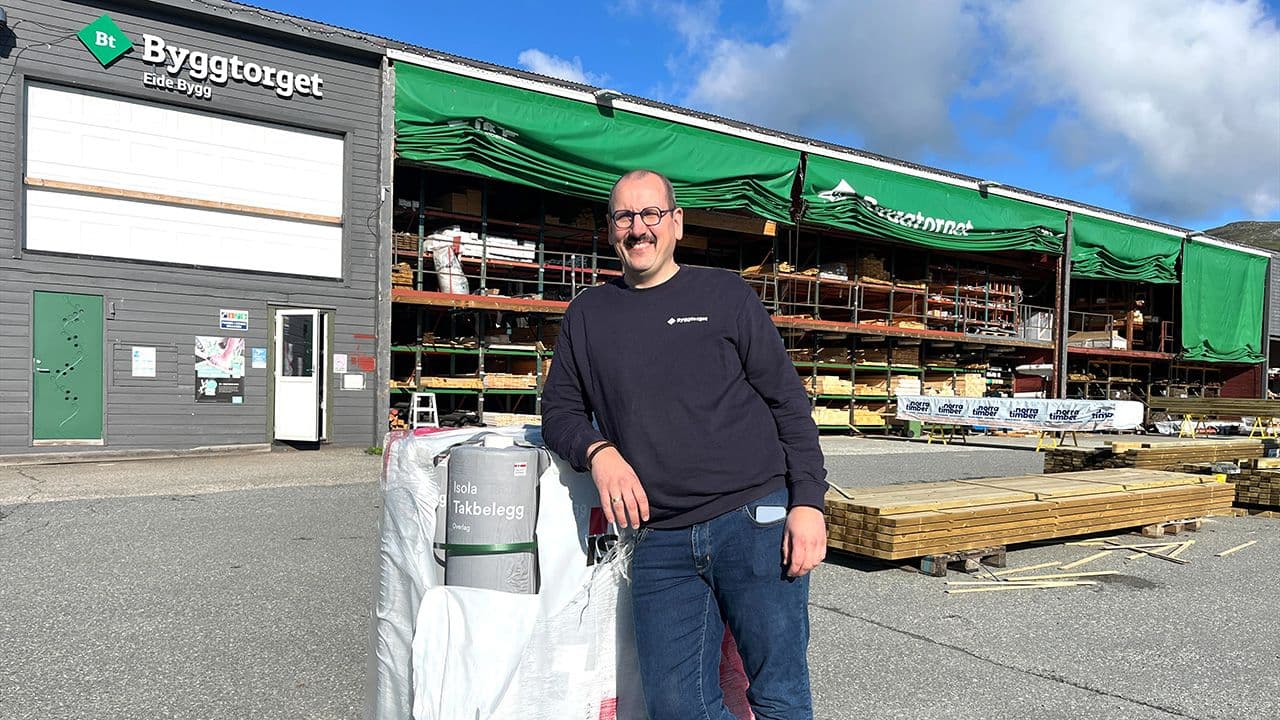 Byggtorget ansatt som smiler til kamera foran byggevarehuset, Byggtorget Eide Bygg