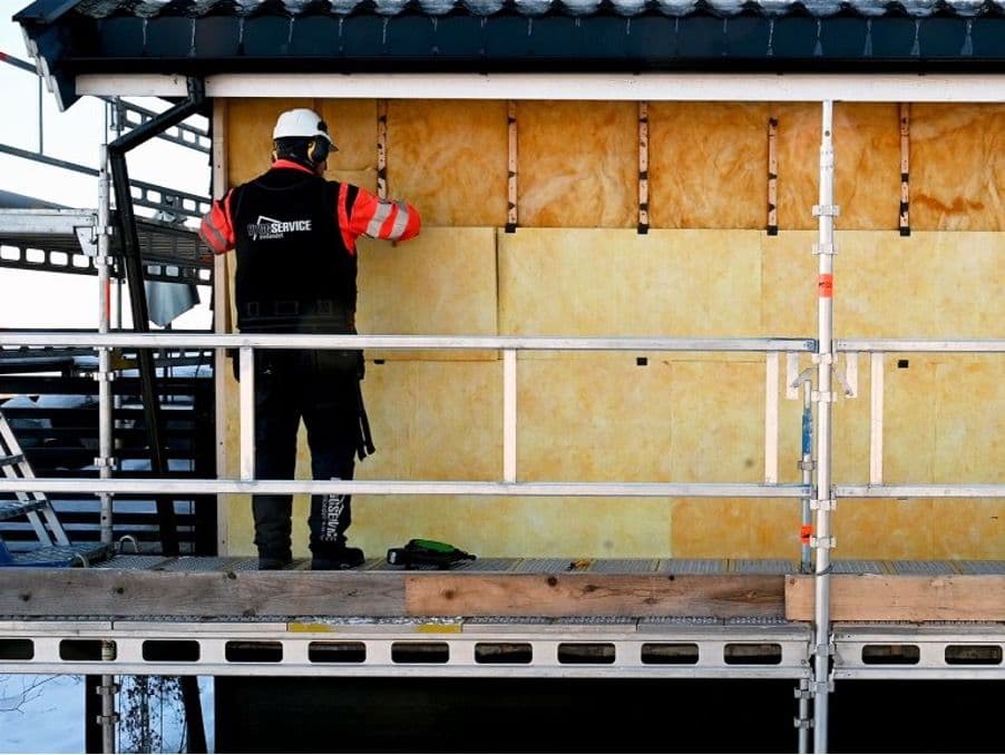 en mann som legger isolasjon på et hus