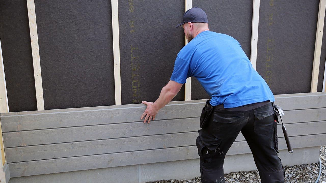 Håndverker som monterer kledning.